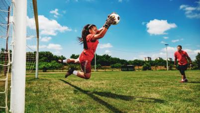 A soccer goalie blocks the ball.