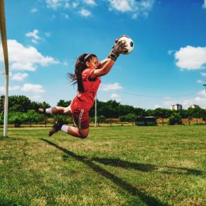 A soccer goalie blocks the ball.