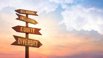 A signpost in front of a sunset. The signs read: Belonging, Inclusion, Equity, and Diversity