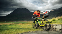 Cyclist in the mountains, checking their bike